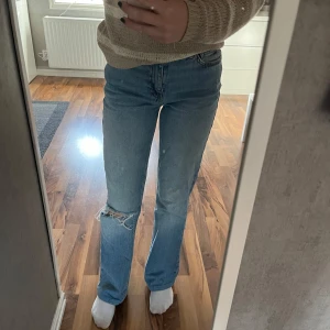Blå jeans med slitningar - Säljer ett par snygga blå jeans med slitningar på ena benet. De är uppsydda och passar bra i längden på mig som är 160cm. Bra skick🤗