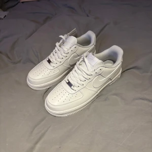 Vita Nike Air Force sneakers - Säljer ett par klassiska vita Nike Air Force sneakers i storlek 42. De är i nytt skick och har den ikoniska designen med snörning och perforerade detaljer på tån. Perfekta för både vardag och fest! ALDRIG ANVÄNDA!