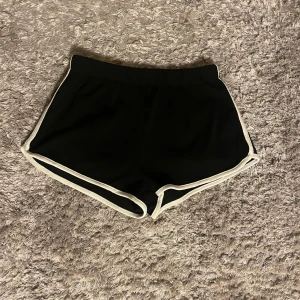 Svarta shorts från Zara - Säljer ett par svarta shorts från Zara i storlek S. De är superbekväma med en elastisk midja och vita kanter som ger en sportig look. Perfekta för sommarens alla äventyr eller bara att chilla i hemma. 🖤