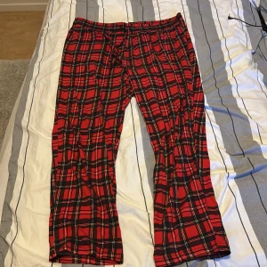 Röda rutiga byxor - Säljer ett par snygga röda pjamas byxor med svart vitt och mörkblått mönster. Perfekt till julen. St XL men funkar även som L. Använda ca 4 gånger. 