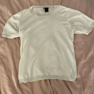 Vit kortärmad topp från Lindex - Säljer en stilren vit topp från Lindex i storlek M. Den är kortärmad och har en normal passform, perfekt för både vardag och fest. Materialet känns mjukt och bekvämt mot huden. Toppen är i mycket bra skick och redo för en ny ägare!💗