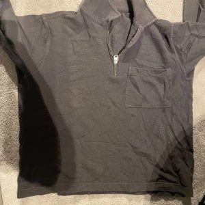 Tröja från Arket - Säljer en enkel och stilren grå tröja med dragkedja och bröstficka från Arket. Perfekt för en avslappnad look. Tröjan har långa ärmar och är i bra skick. Passar till både vardag och chill.