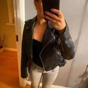 Svart skinnjacka från Zara - Säljer en snygg svart skinnjacka från Zara i storlek S. Jackan har en cool bikerstil med dragkedja och knappar. Perfekt för höst och vår, och funkar lika bra till fest som till vardags. Den är i mycket bra skick och redo för nya äventyr! 🖤
