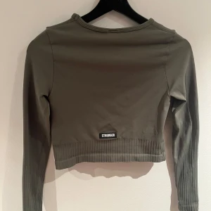 Träningströja stronger - Militärgrön träningströja från Stronger, ser grå ut på bilderna men är mer åt det mörk/militärgröna hållet. Knappt använd, storlek S.  Bara att skriva för fler bilder 💞💞