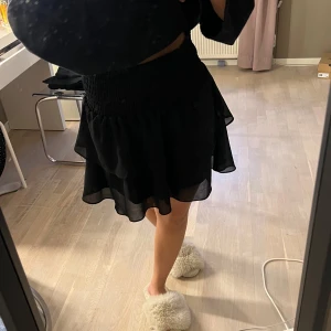 Svart kortkjol med volang - säljer denna svarta kortkjol med volangdetaljer. den är i mycket bra skick och är också väldigt fin att använda som topp 🖤