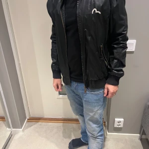 Svart skinnjacka - Säljer en snygg svart skinnjacka från märket Evisu.  Storleken är XL men mer åt M 