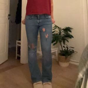 Blå jeans med slitningar - Säljer ett par snygga blå jeans med slitningar på låren och knäna. De har en klassisk femficksdesign och en bekväm passform. Perfekta för en avslappnad vardagslook! 🕶️
