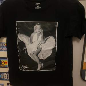 Säljer en svart t-shirt från Jayhu i storlek XS. Den har ett coolt tryck av en ikonisk bild på framsidan. Perfekt för en avslappnad stil eller att bära på fest. T-shirten är i bra skick och gjord av mjukt material.