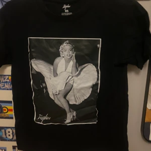 Svart tisha,   PRIS kan diskuteras  - Säljer en svart t-shirt från Jayhu i storlek XS. Den har ett coolt tryck av en ikonisk bild på framsidan. Perfekt för en avslappnad stil eller att bära på fest. T-shirten är i bra skick och gjord av mjukt material.