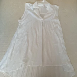 Vit ärmlös blus - Säljer en elegant vit ärmlös blus i mycket bra  skick. Den har en luftig passform med plisserad detalj baktill som ger en fin rörelse. Perfekt för sommarens alla tillfällen! 🌞
