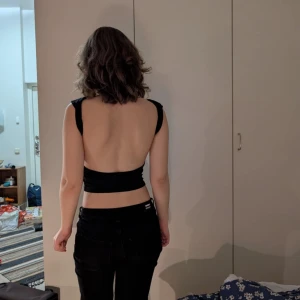 Svart ärmlös croppad topp - Säljer en stilren svart ärmlös topp som är croppad och perfekt för sommaren. Toppen har en tight passform och är gjord i ett mjukt material som sitter skönt mot huden. Den är enkel men ändå chic, perfekt för både vardag och fest!