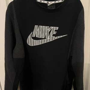 Svart långärmad tröja från Nike - Säljer en svart långärmad tröja från Nike med deras ikoniska logga i vitt på bröstet. Tröjan är i mycket bra skick och perfekt för både träning och vardag. Den har en bekväm passform och är gjord i mjukt material.