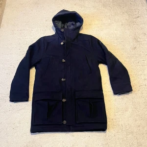 Boomerang Jacka - Säljer en snygg mörkblå kappa från Boomerang i storlek M. Den har en huva och knappar framtill. Perfekt för höst och vinter med sin varma och stilrena design. Passar både till vardags och lite finare tillfällen. 🧥
