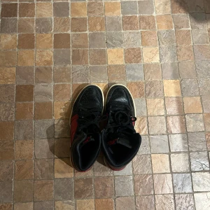 Nike Air Jordans i svart och rött - Säljer ett par klassiska Nike Air Jordans i svart och rött. Skorna har en snygg design med snörning och en bekväm passform. Perfekta för både vardag och fest! De är i bra skick med lite slitage på sulan.