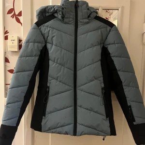 Vinter/skidjacka - En perfekt vinterjacka som funkar bra i både vardagen eller på fjällresan! Riktigt varm å go jacka som håller en varm under vintern Säljer då den har blivit lite för liten och vill därför köpa en annan Lite lite små sminkfläckar kvar efter tvätt längst upp vid dragkedjan (se bild) samt en fläck på baksidan av luvan (se bild) vet ej om den går bort. En grön/turkos/blå-aktig färg med svarta detaljer