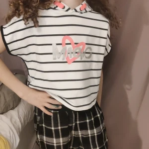 Randig kortärmad hoodie med tryck - Säljer en superfin vit och svart randig hoodie med korta ärmar. Den har ett coolt tryck med texten 'Magic' och ett rosa hjärta på framsidan. Perfekt för en avslappnad stil! 🖤