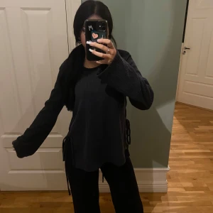 Mörkgrå tröja från zara - Säljer en helt oanvänd tröja från Zara. Tröjan har en snygg knytning i sidan som ger en extra detalj. Den är lite för lång för mig.