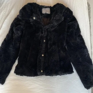 Svart pälsjacka från vero moda - Säljer en supermjuk och fluffig svart pälsjacka som är köpt från veromoda. (Slutsåld) Den  knappar framtill med silkestyg på insidan. Perfekt för att hålla sig varm och stilren under kyliga höstdagar 🍂. Passar både till vardags och festliga tillfällen. 🖤