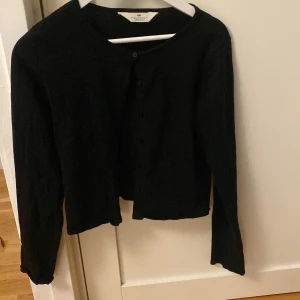 Svart kofta  - Säljer en stilren svart kofta. Den har långa ärmar och knappar framtill. Perfekt för både höst och vintern. 