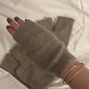 Stickade torg vantar  - Säljer ett par mysiga stickade fingerlösa vantar i olika färger. Perfekta för att hålla händerna varma samtidigt som du kan använda mobilen. Finns i beige, grå och svart. De är mjuka och stretchiga, vilket gör dem bekväma att bära hela dagen. Finns bara beige kvar!!!