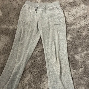Grå juicy couture byxor🩶 - Superbekväma grå mjukisbyxor i bomull med snörning i midjan. De har en avslappnad passform och praktiska fickor både fram och bak. Perfekta för en chill dag hemma eller en snabb tur till affären. Tappat ena metall pluppen som sitter på snöret men annars i väldigt bra skick!🤍 Priset var 1200 när jag köpte de. 
