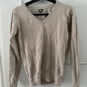 Beige tröja från Cubus - Säljer en stilren beige tröja från Cubus i storlek M. Tröjan har en v-ringad hals och långa ärmar med ribbade muddar. Perfekt för en avslappnad look.