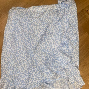 Blommig kjol från Vero Moda - Söt ljusblå kjol med vita blommor från Vero Moda. Kjolen har en knytning i midjan och är perfekt för sommarens varma dagar. Tillverkad i ett lätt och bekvämt material.