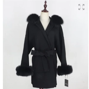 Svart kappa med pälsdetaljer - Elegant svart kappa med mjuka pälsdetaljer på krage och ärmslut, som går att knappa av vid tvätt eller om man nån gång vill använda kappan utan pälsdetaljerna. Kappan har ett knytbälte i midjan för en justerbar passform. Perfekt för kyligare dagar när du vill känna dig både varm och stilren. (äkta päls därav högre pris). Hör av er vid mer frågor, om ni vill ha mer detaljer och bilder!🙌🏼😊