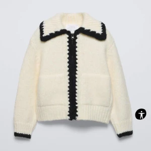 Vit stickad jacka med svarta detaljer - Snygg vit stickad kofta med kontrasterande svarta detaljer längs dragkedjan och kragen. Extremt mjuk och härlig! Fickor på båda sidor. Storlek 164 skulle säga XS/S! (Helt ny med lapp) 