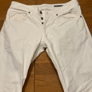 Vita byxor från Dondup - Snygga vita byxor från Dondup med knappgylf och femficksdesign. Tillverkade i Italien, dessa byxor har en stilren look och passar perfekt för en trendig outfit. Märkesdetaljer syns på baksidan.