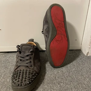 Svarta sneakers med nitar - Snygga gråa Loubs med alla nitar kvar och röd sula!. Dem är lite slitna under skon då dem är använda lite! Men dom är i fortfarande i väldigt bra skick!. Dem är i storlek 40 men är ganska stora i storleken. Tveka inte att höra av er! Boxen till skorna medföljer. Obs Inte äkta!☀️