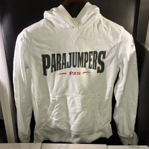 Vit hoodie från Parajumpers - Säljer en vit hoodie från Parajumpers med stor logga på framsidan och ett märke på ärmen. Hoodien är tillverkad i fleece och har en klassisk känguruficka framtill. Den har en del fläckar som syns på bild 3 och 5, annars bara skrynklig men fint skick. Perfekt för kyliga dagar! Hör av er vid minsta fundering🙌