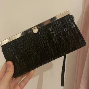 Aftonväska - Aftonväska/kuvertväska med jättefint mönster💞 perfekt för både fest och vardag. Sparsamt använd. Lite fläckig på metallen men annars i gott skick. 19cmx9,5cm