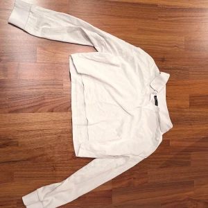 Vit henley-skjorta - Snygg vit henley-skjorta med långa ärmar och klassisk design. Perfekt för en stilren look. Tillverkad i mjukt material för extra komfort.