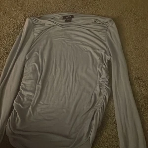 Ljus blå långärmad topp från Lindex - Säljer en stilren ljus blå långärmad topp från Lindex. Toppen har rynkade detaljer på sidorna som ger en snygg effekt. Perfekt för en avslappnad men ändå chic look. Tillverkad i Turkiet.