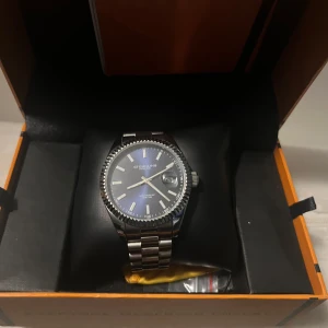 Stührling Original klocka i silver - Säljer en elegant Stührling Original klocka med silverfärgad boett och armband. Klockan har en stilren urtavla med tydliga markeringar och datumvisning. Perfekt för den som söker en klassisk och tidlös design. Pris kan diskuteras👍