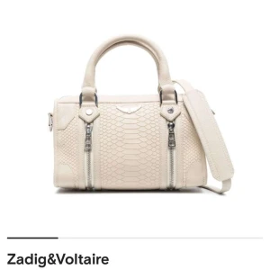 Beige handväska från zadig & Voltaire  - Elegant beige handväska med reptilmönster och dubbla handtag från Zadig & Voltaire. Väskan har en avtagbar axelrem och dragkedjedetaljer framtill. Perfekt för en stilren look. Knappt använd. Nypris 6100kr. Pris kan diskuteras! Skriv för fler bilder💞
