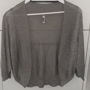 Glittrig kofta - En grå glittrig kofta som inte kommer till användning. Jätte bra skick då den inte har några defekter.