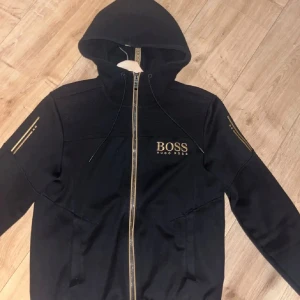 Hugo Boss Zip & Hugo Boss Sweatshirt - En svart/guldig Hugo Boss Zip Kofta. Och en grön Hugo Boss SweatShirt. Sweatshirt kvalite som helt ny men zipen lite solblekt