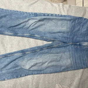 Blå jeans från Bershka - Snygga blå jeans från Bershka i en klassisk mom fit. De har en hög midja och en avslappnad passform som ger en trendig look. Perfekta för en casual stil.