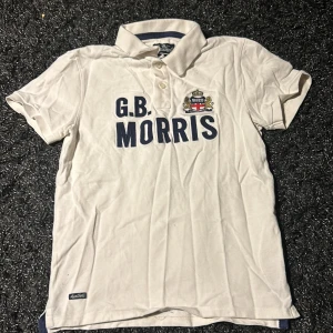 Vit kortärmad pikétröja från Morris - Snygg vit pikétröja från Morris med broderad logga och texten 'G.B. Morris' på bröstet. Tröjan har en klassisk krage och korta ärmar, perfekt för en stilren look. Storlek medium egentligen men skulle mer säga att den passar S!