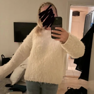 Vit fluffig tröja - Mysig vit tröja med fluffig textur. Perfekt för kyliga dagar och ger en stilren look. Långärmad design som passar bra till jeans eller kjol.