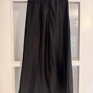 Svart sidenkjol - Svart sidenkjol från Gina Tricot med dekorativa knappar framtill. Sparsamt använd. Storlek 36