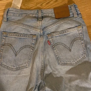 Levis jeans - Ljusblå Levis jeans i modellen High ribcage straight Storlek W25  Slitning i rumpan och uppsprättade i benslutet, men går säkert att laga och sy upp dom igen 
