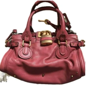 Chloe Paddington väska - DETALJER Material: Läder  Färg: Röd  Tillbehör: Inga  ANGE Exteriör: I gott skick, med några små tecken på användning.  Insida: I gott skick.  MÅL Centimeter: Bredd 30,5 x Höjd 24,5  Tum: Bredd 12,1 x Höjd 9,7 