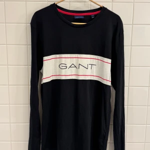 Marinblå långärmad T-shirt från Gant – Storlek M - Marinblå långärmad T-shirt från Gant i storlek M. Plagget är i fint skick och erbjuder både komfort och stil.