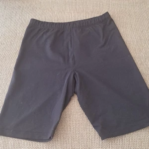Svarta shorts med snörning - Säljer ett par svarta shorts i bomull. De har en bekväm passform med elastisk midja och snörning för justering. Perfekta för en avslappnad dag eller träning.