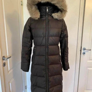 Vinterjacka  - Tommy hilfiger dunjacka lång. Är 168 lång och jackan kommer till vaderna. Varm vinterjacka som håller värmen.   Färg: svart. Str: S, lite figursydd. Använd skick 