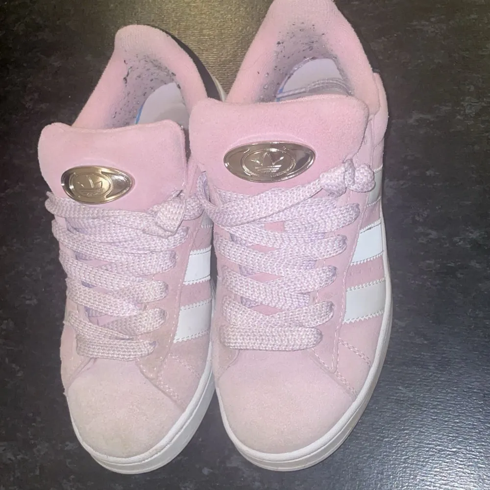 Säljer ett par snygga rosa sneakers med breda snören och en cool silverdetalj på plösen. Skorna har en vit sula och är perfekta för en avslappnad stil. De är i bra skick och redo för nya äventyr!. Skor.