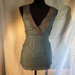 Bobo linne - Ett vackert blått över tyg på en skimrande blå/guldigt tyg med en brun lace. Väldigt vackert linne med stor öppning för framme. Du kan välja att knyta där bak med tråden eller ha det löst. Väldigt skön att ha på sig 